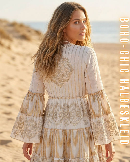 Nahaufnahme der Rückseite eines weißen Boho-Chic-Halbkleides am Strand, die detaillierte goldene Stickerei und die gestuften Glockenärmel zeigt. Frau blickt über die Schulter zurück. Vertikaler Text: BOHO-CHIC HALBESKLEID.