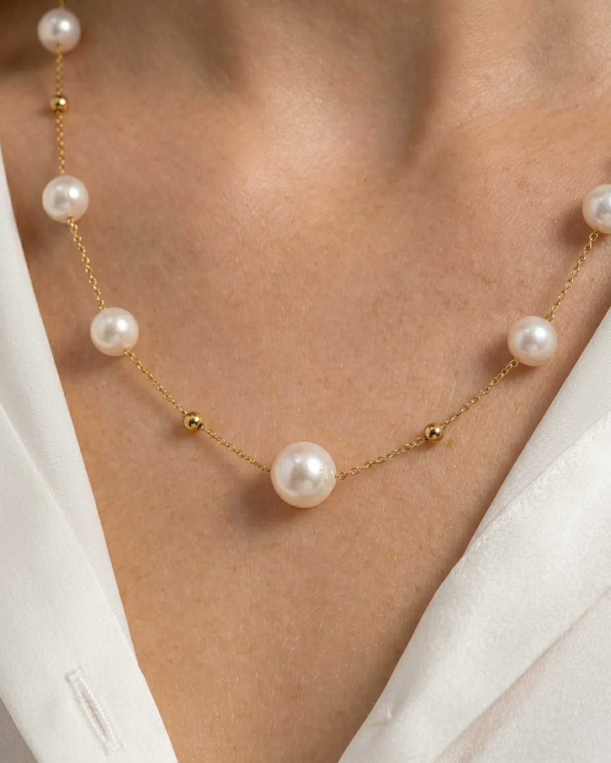 Detailansicht der zarten Gliederkette auf der Haut mit Fokus auf die glänzenden Imitationsperlen und die goldenen Zwischenelemente.