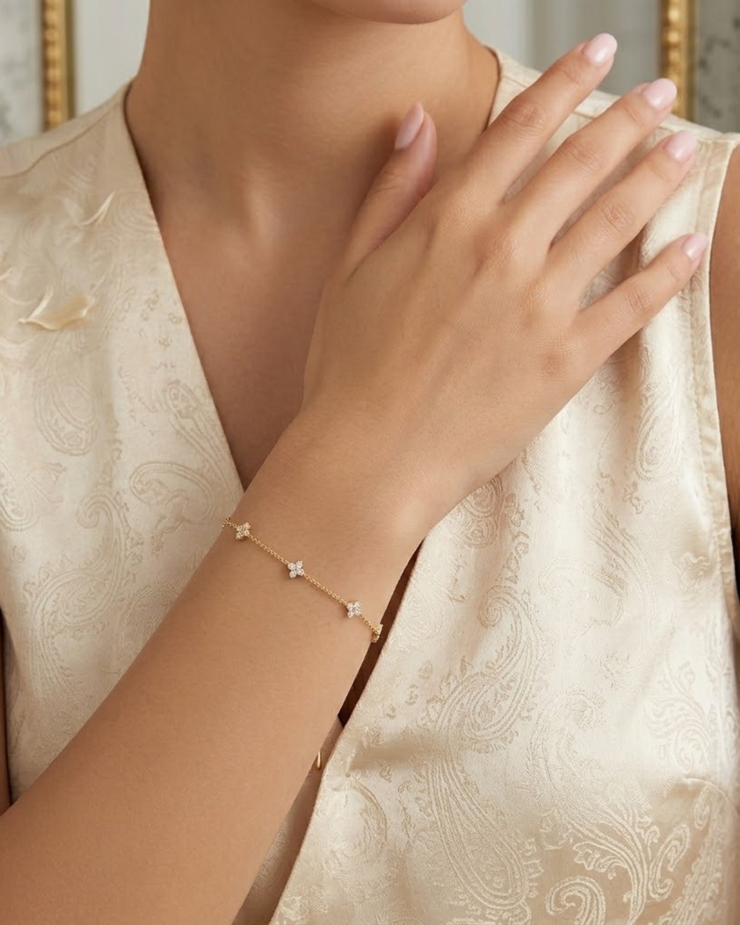Detailansicht des filigranen Damenarmbands mit glitzernden Anhängern, getragen zu einer eleganten Bluse mit Paisley-Muster.