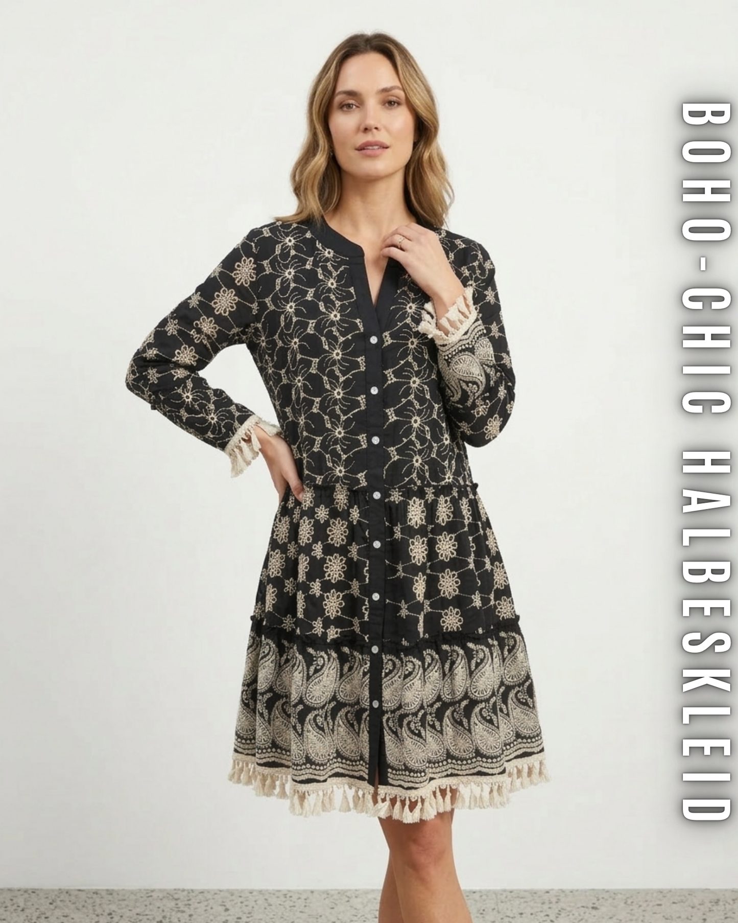 Frontansicht schwarzes Bohemian-Kleid mit aufwendiger Paisley-Lochstickerei und Fransen, Stufenkleid für Damen vor weißem Hintergrund.