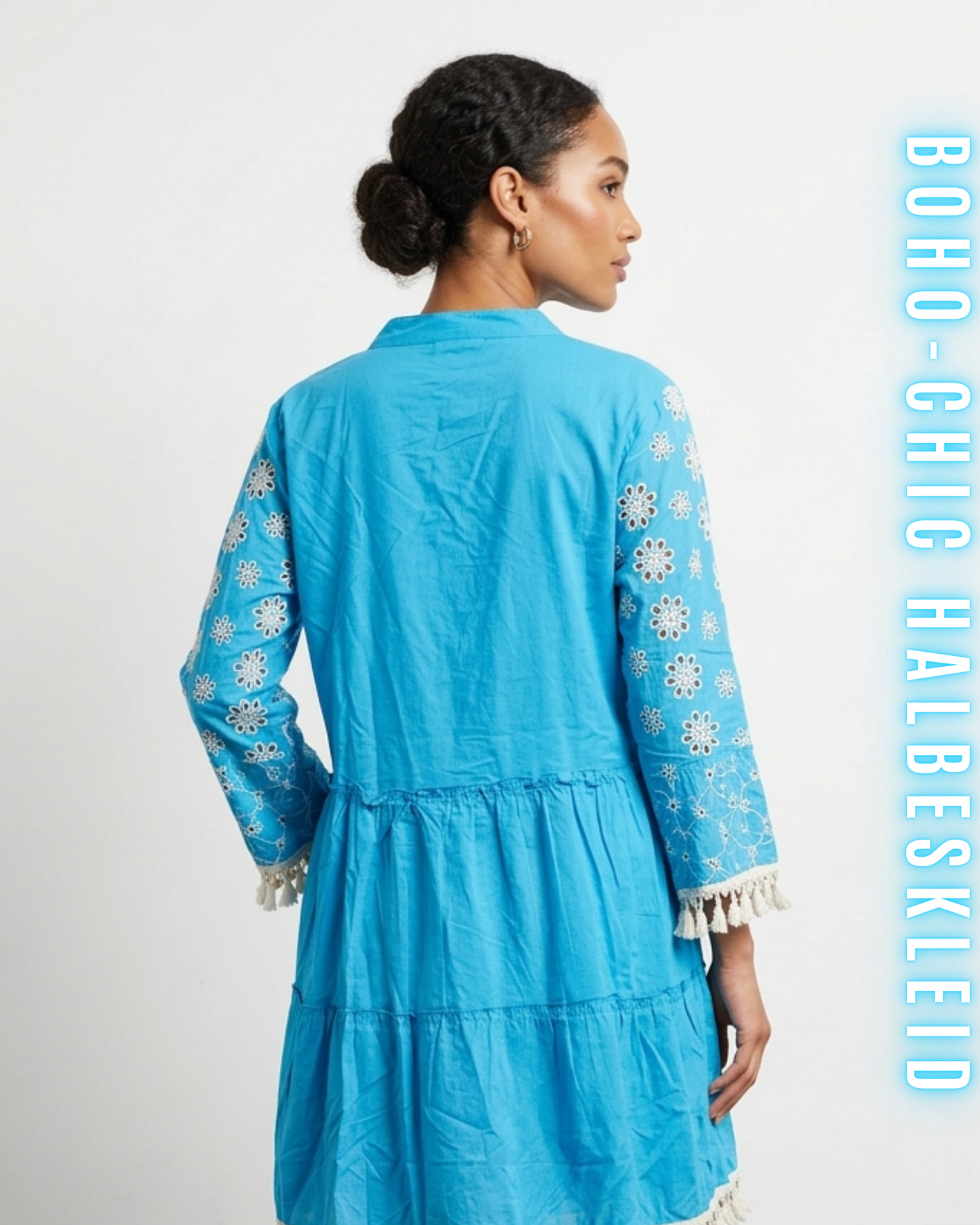 Nahaufnahme der Rückseite eines leuchtend blauen Boho-Chic-Mini-Kleides vor einem schlichten weißen Hintergrund, mit Quastenfransen-Details an den Ärmelbündchen und einer gestuften Rocknaht. Beinhaltet den Text BOHO-CHIC HALBESKLEID.