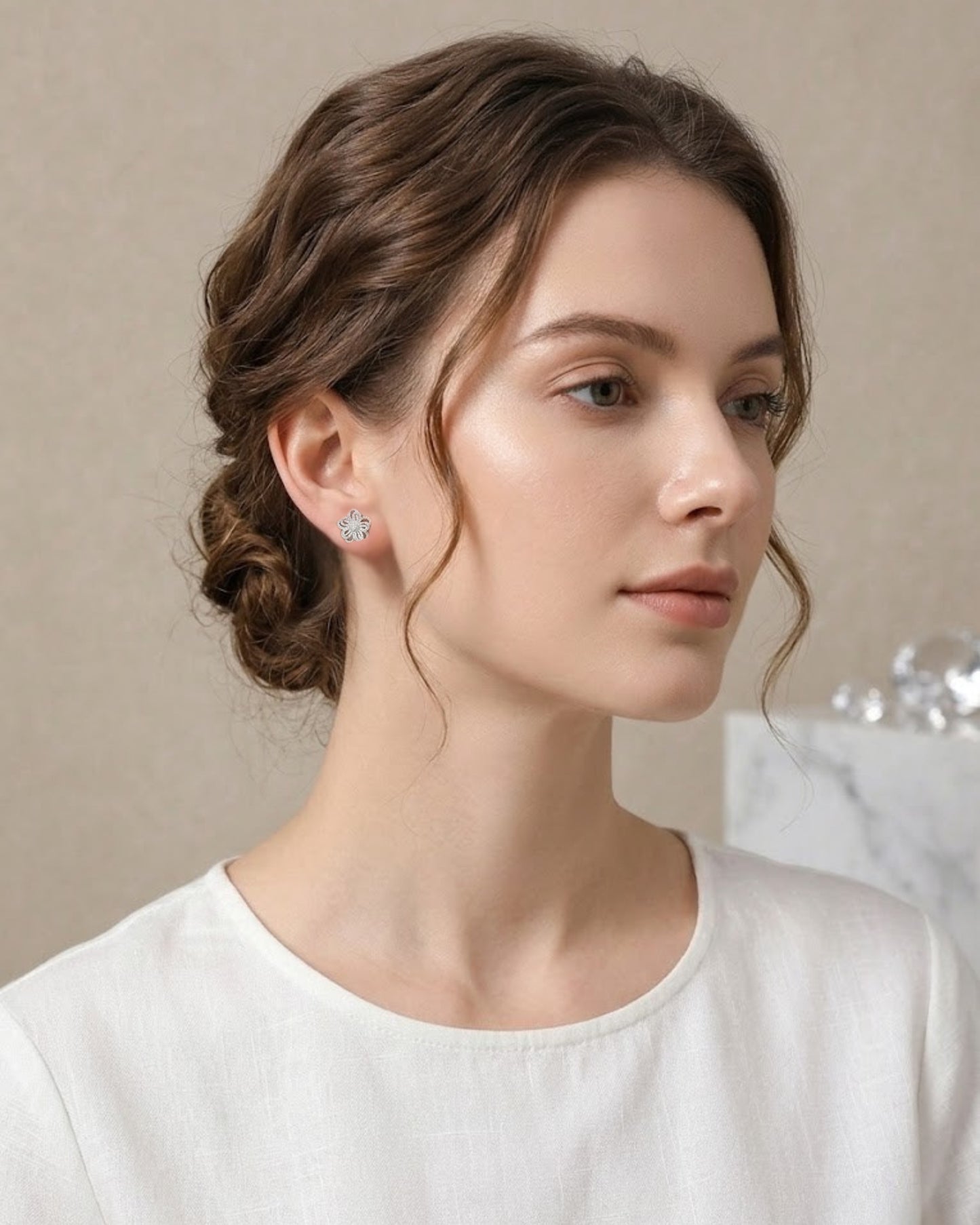 Seitenprofil einer Frau mit elegant hochgestecktem Haar, die den zierlichen, silberfarbenen Blüten-Ohrstecker am Ohr trägt.