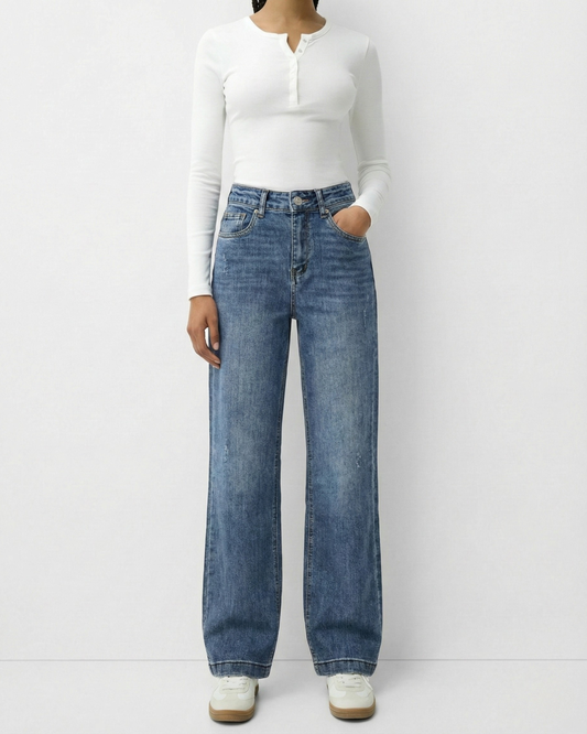 Frau trägt eine mittelblaue High-Waist Straight Leg Jeans kombiniert mit einem weißen Langarmshirt.
