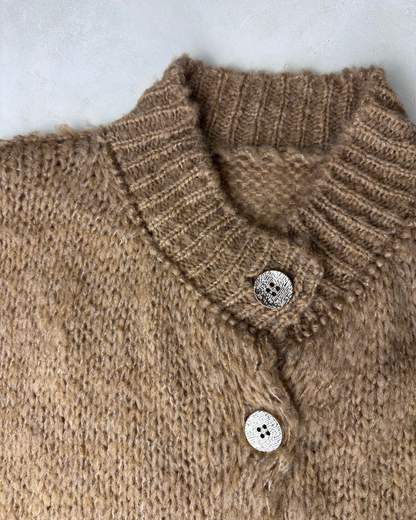 Nahaufnahme des braunen, gerippten Kragens und der glänzenden Knöpfe des Cardigans.