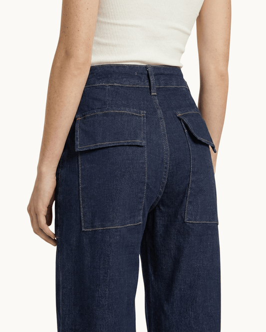 Rückansicht der dunkelblauen Denim-Hose mit Fokus auf die Gesäßtaschen mit Klappen.
