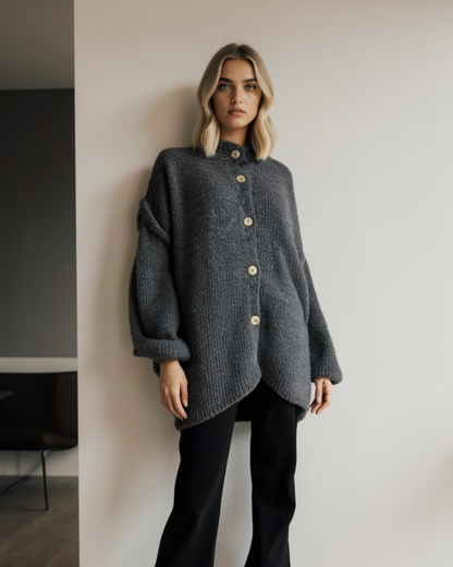 Ganzkörperansicht einer Frau in einem grauen, kurzen Strickcardigan mit hellen Knöpfen.