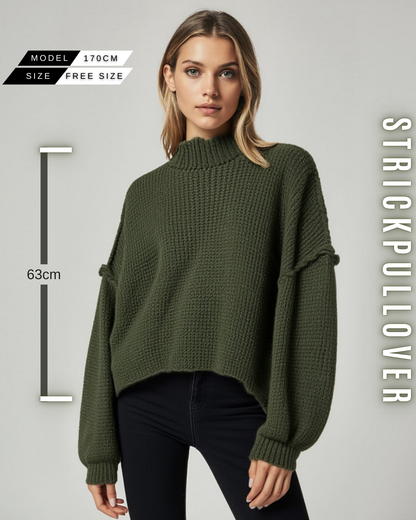 Eine Frau in einem tannengrünen, grob gestrickten Pullover mit Stehkragen, weiten Ärmeln und mit Größe Information.