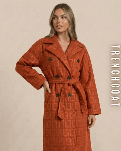 Frontansicht einer Dame in einem orangen Monogramm Trenchcoat mit Taillengürtel.