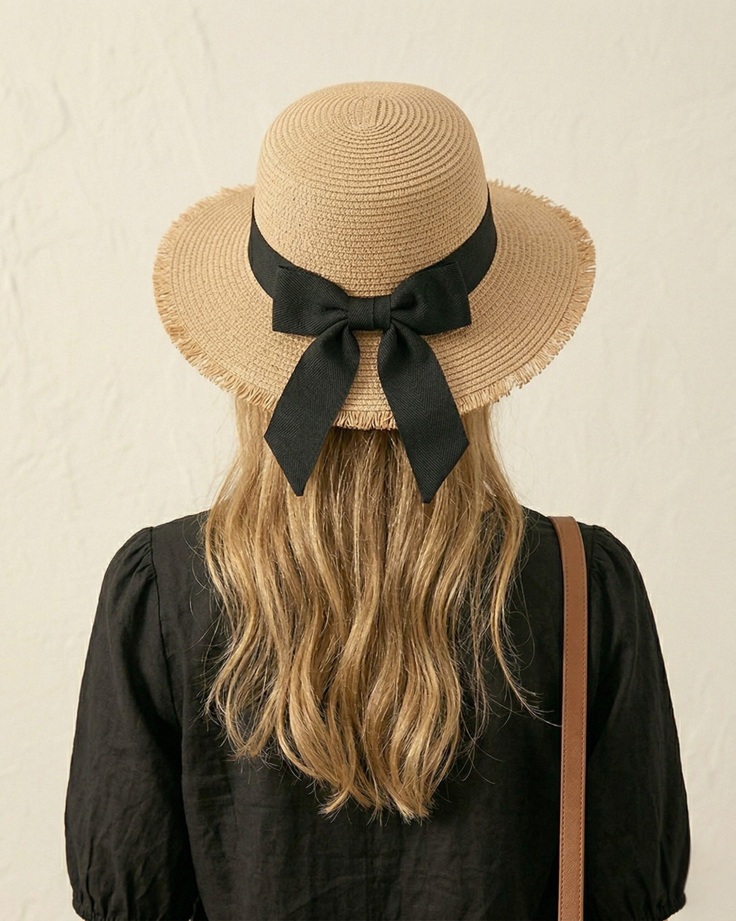 Rückansicht des ELEXUA „MILA“ gefransten Strohhuts mit der markanten schwarzen Schleife.