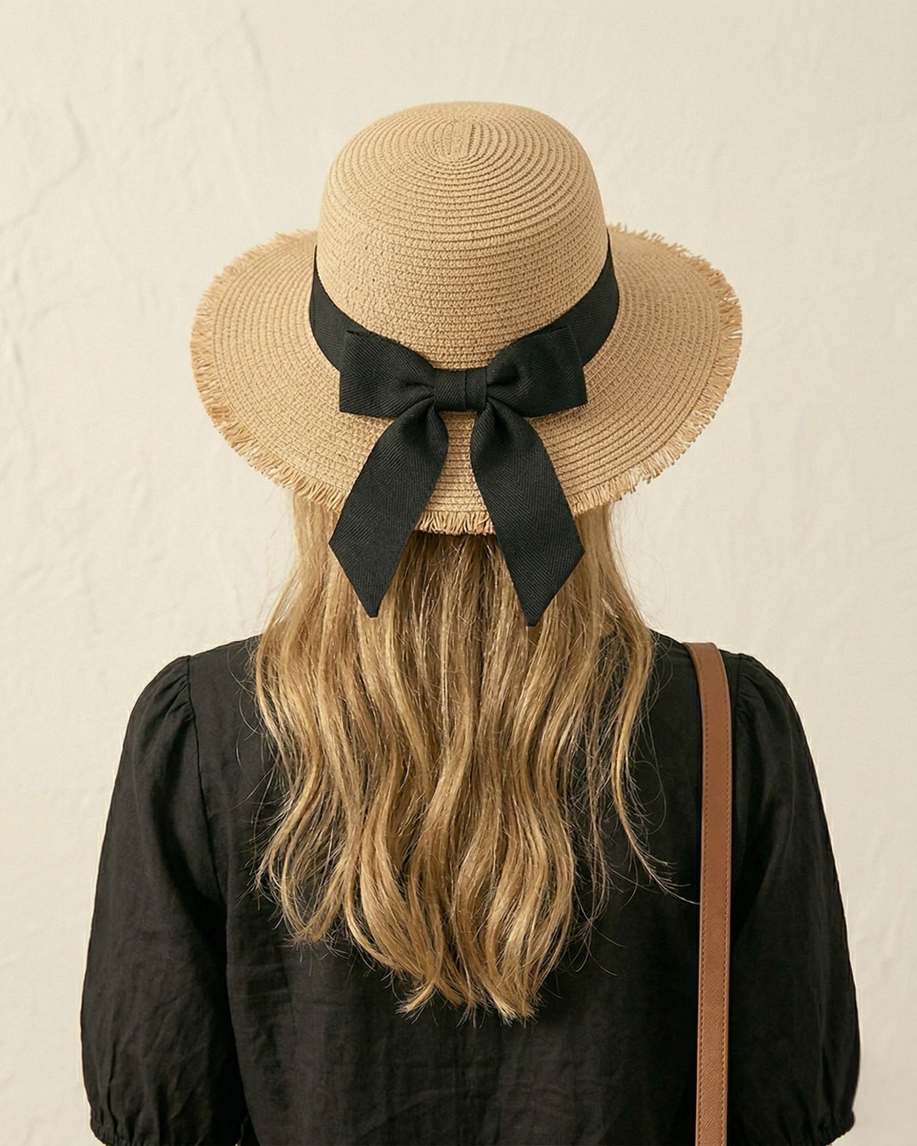 Rückansicht des ELEXUA „MILA“ gefransten Strohhuts mit der markanten schwarzen Schleife.