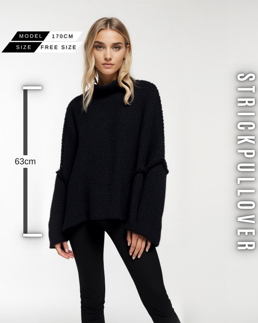 Eine Frau in einem scwarzen, grob gestrickten Pullover mit Stehkragen, weiten Ärmeln und mit Größe Information.