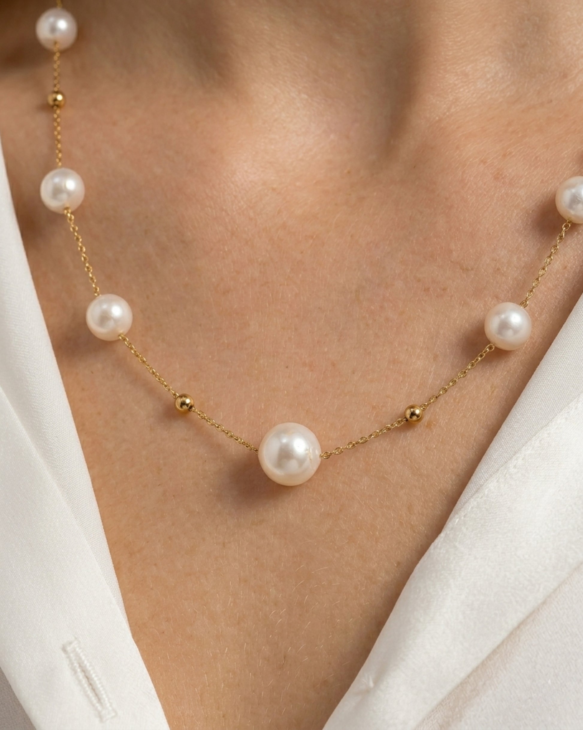 Detailansicht der zarten Gliederkette auf der Haut mit Fokus auf die glänzenden Imitationsperlen und die goldenen Zwischenelemente.