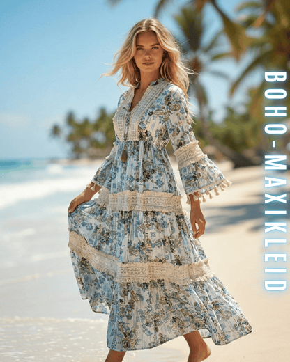Frontansicht einer Frau im weißen Boho-Maxikleid mit blauen Blumen am Strand.