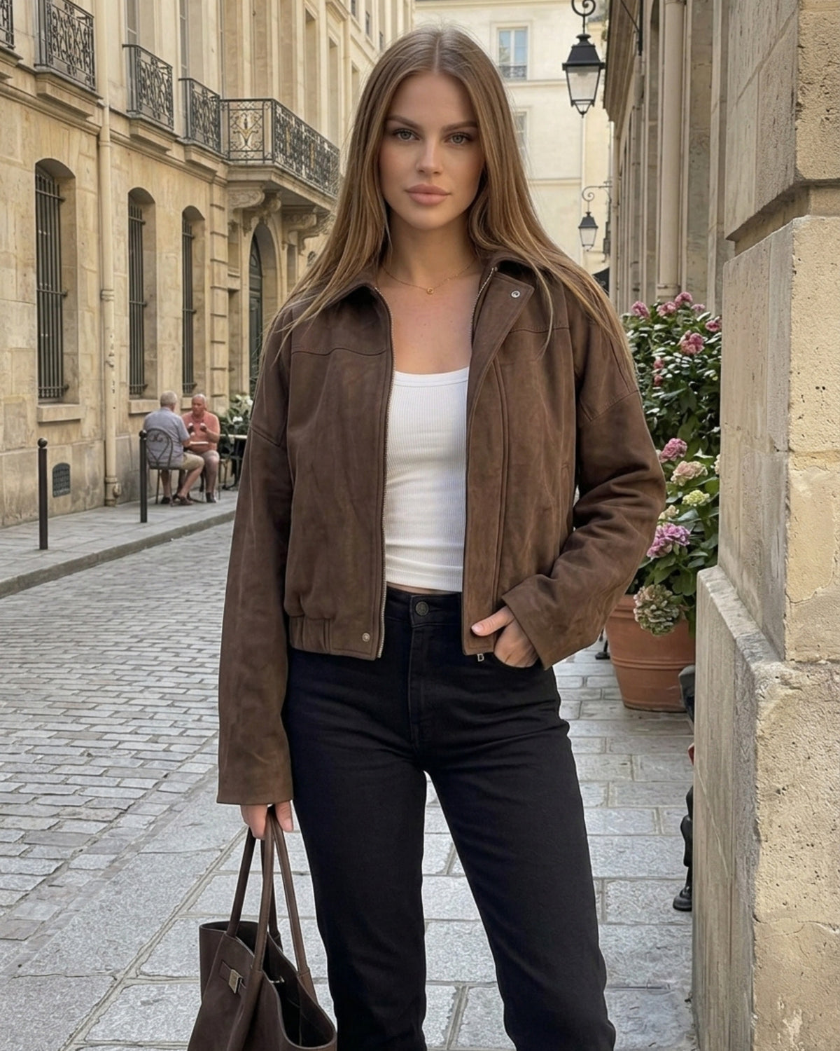 Frau trägt kurze braune Übergangsjacke offen über weißem Top mit schwarzer Stoffhose