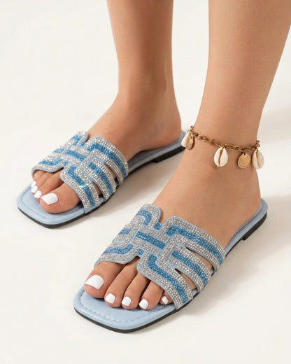 Schräge Vorderansicht der eleganten Damen-Strass-Sandalen mit offener, quadratischer Zehenpartie auf weißem Hintergrund.