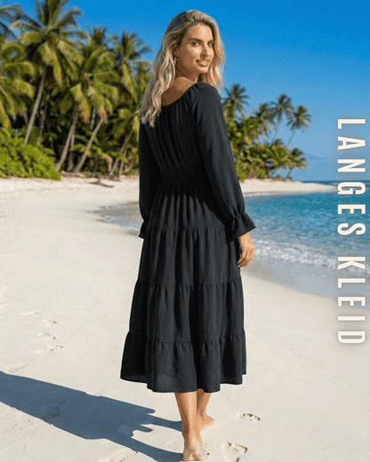 Elegantes schwarzes langes Kleid von ELEXUA mit Knopfleiste und gesmokter Taille, getragen am sommerlichen Strand.