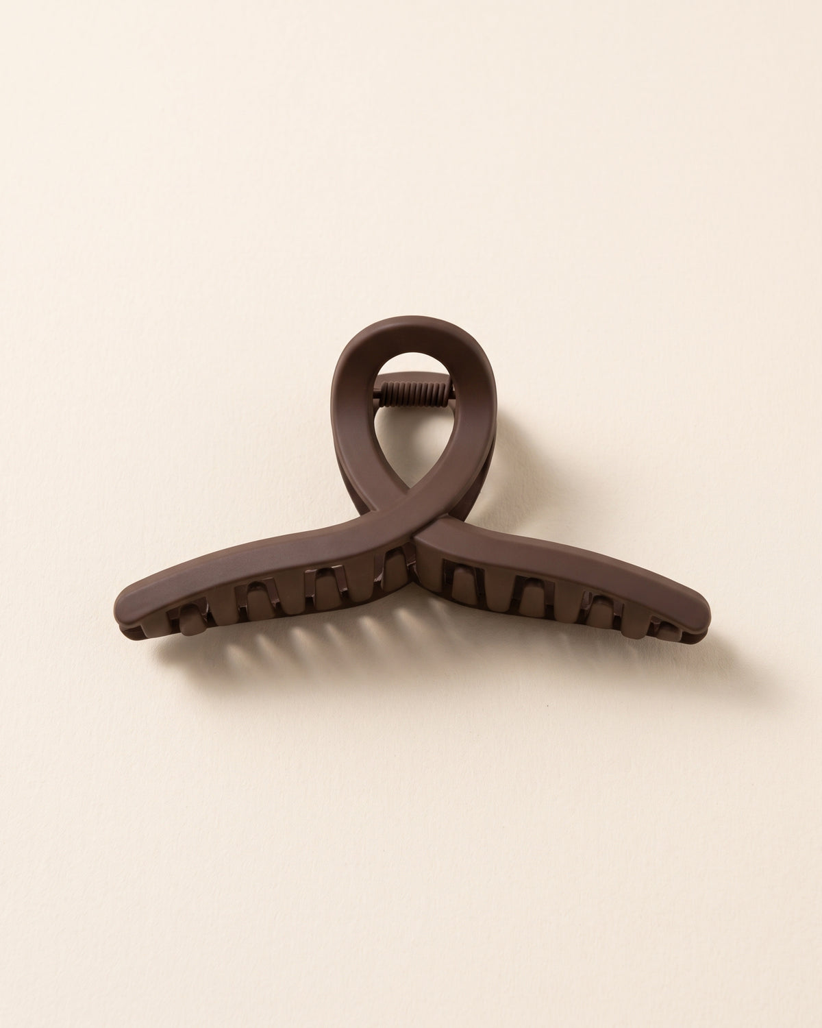 Dunkelbraune matte Haarklammer in minimalistischem Design auf beigem Hintergrund