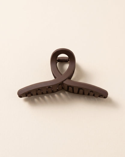 Dunkelbraune matte Haarklammer in minimalistischem Design auf beigem Hintergrund