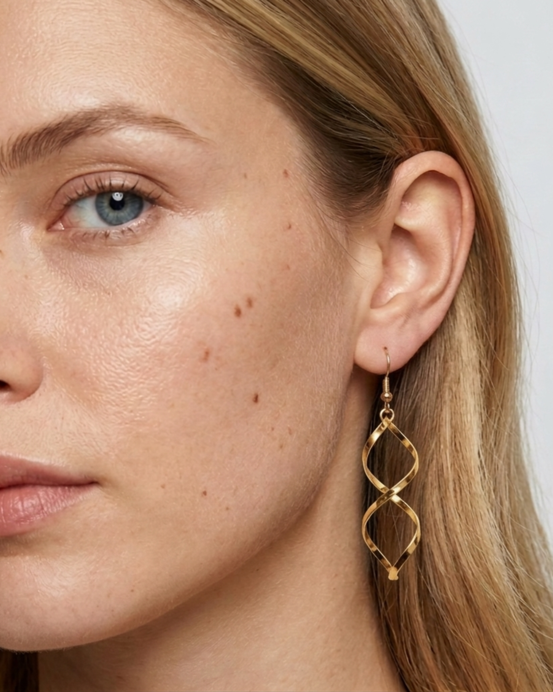 Detailansicht der goldenen Twisted Hängeohrringe am Ohr getragen.