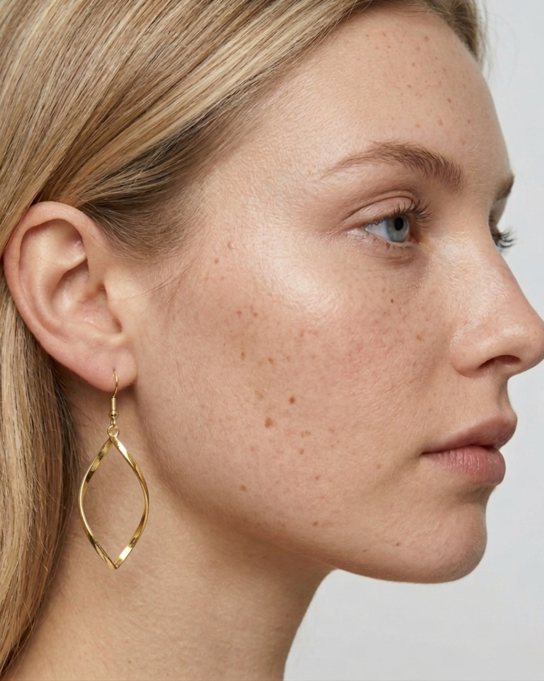 Seitenprofil-Ansicht eines Models, das einen goldenen TWIST Ohrring trägt.