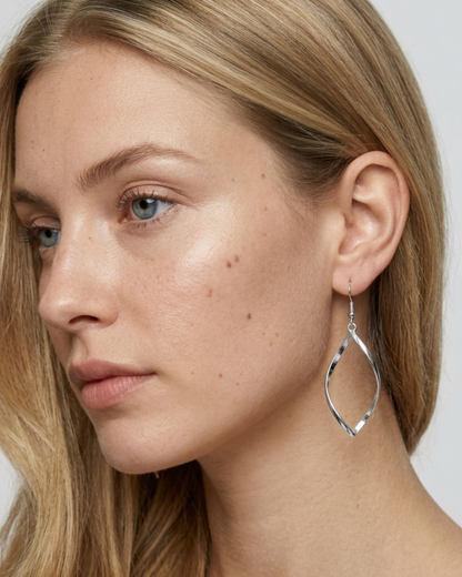 Nahaufnahme eines silbernen ELEXUA TWIST Twisted-Hängeohrrings am Ohr eines Models.