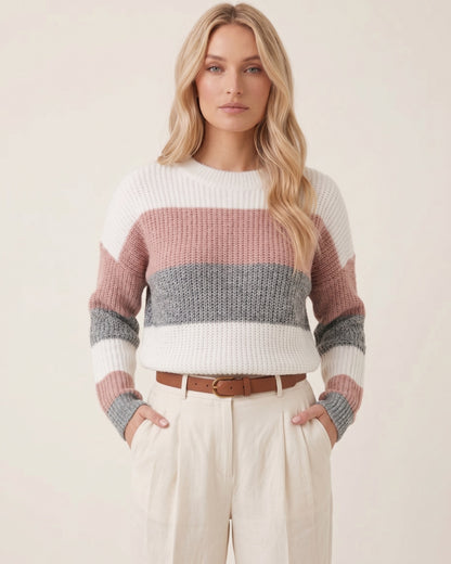 Blondes Model trägt dreifarbigen Strickpullover mit Blockstreifen in Rosé, Grau und Weiß zu beiger Chino