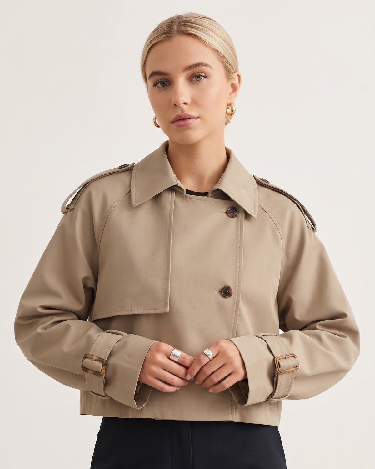 Model trägt kurzen sandbeigen Trenchcoat hochgeschlossen mit Reverskragen und Schulterklappen