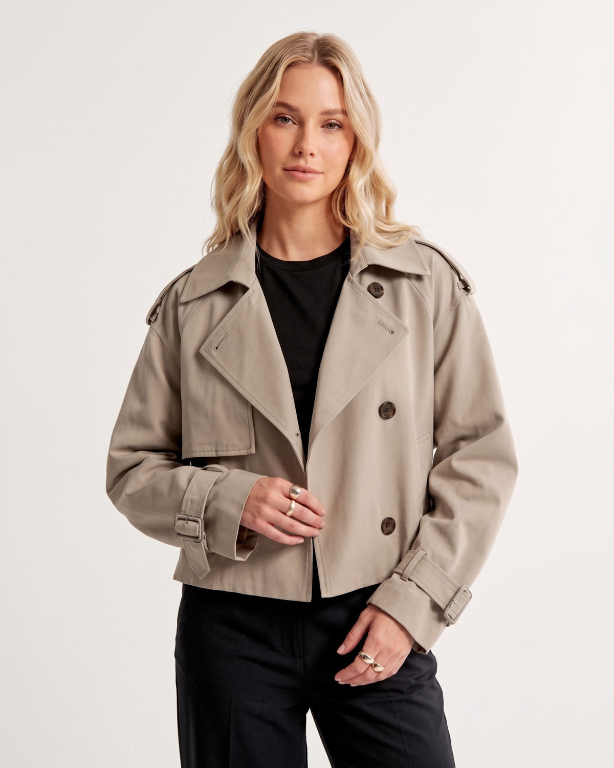 Locker geschnittene Cropped Trenchjacke geöffnet getragen zu schwarzem Shirt und Bundfaltenhose