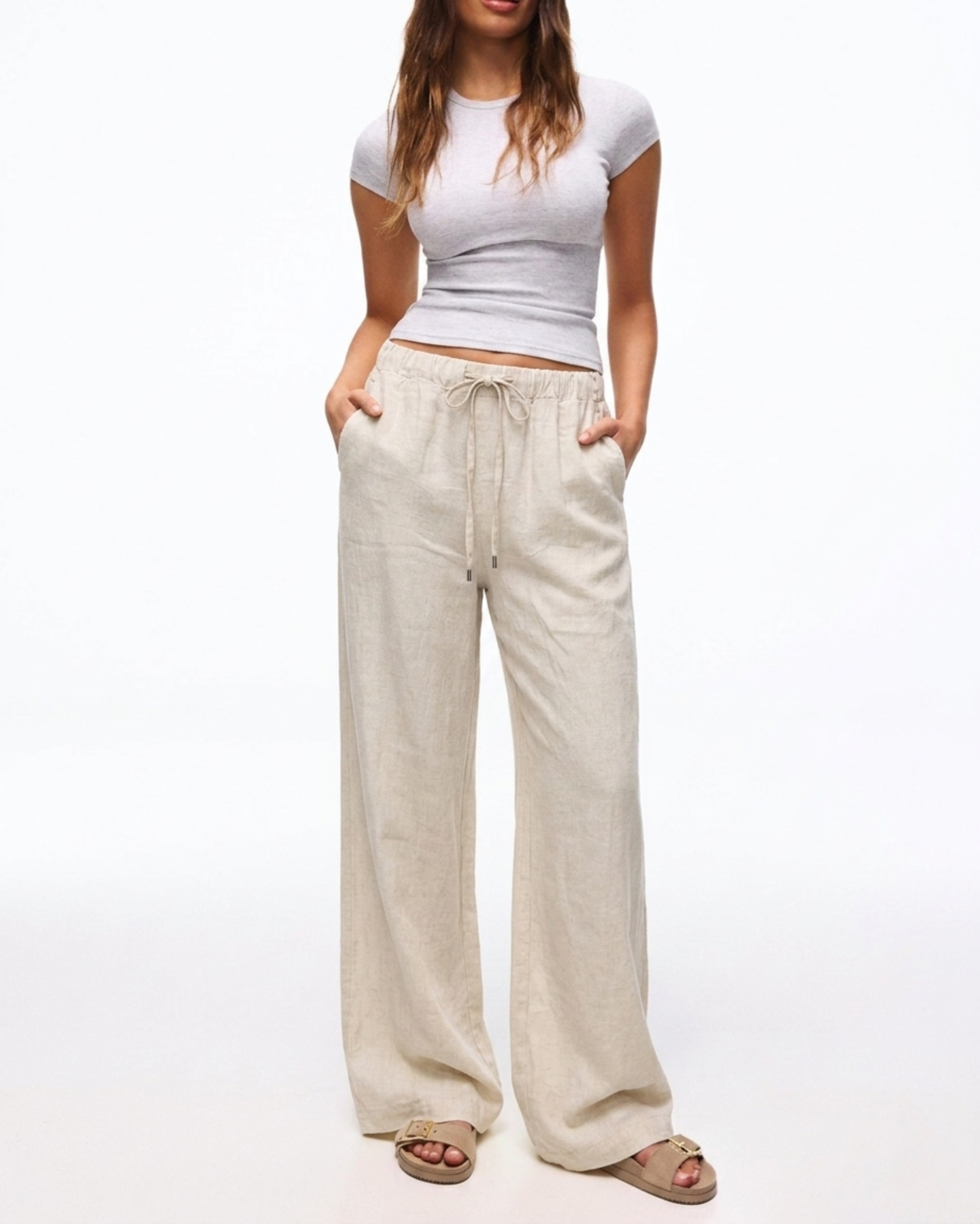 Damen trägt die beige Leinenhose mit weitem Bein und Kordelzug.