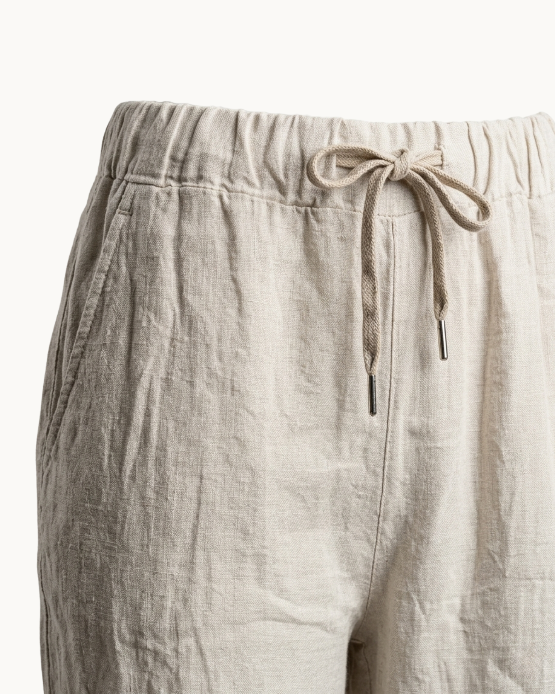 Detailaufnahme des elastischen Bunds und des Kordelzugs der beigen Hose.