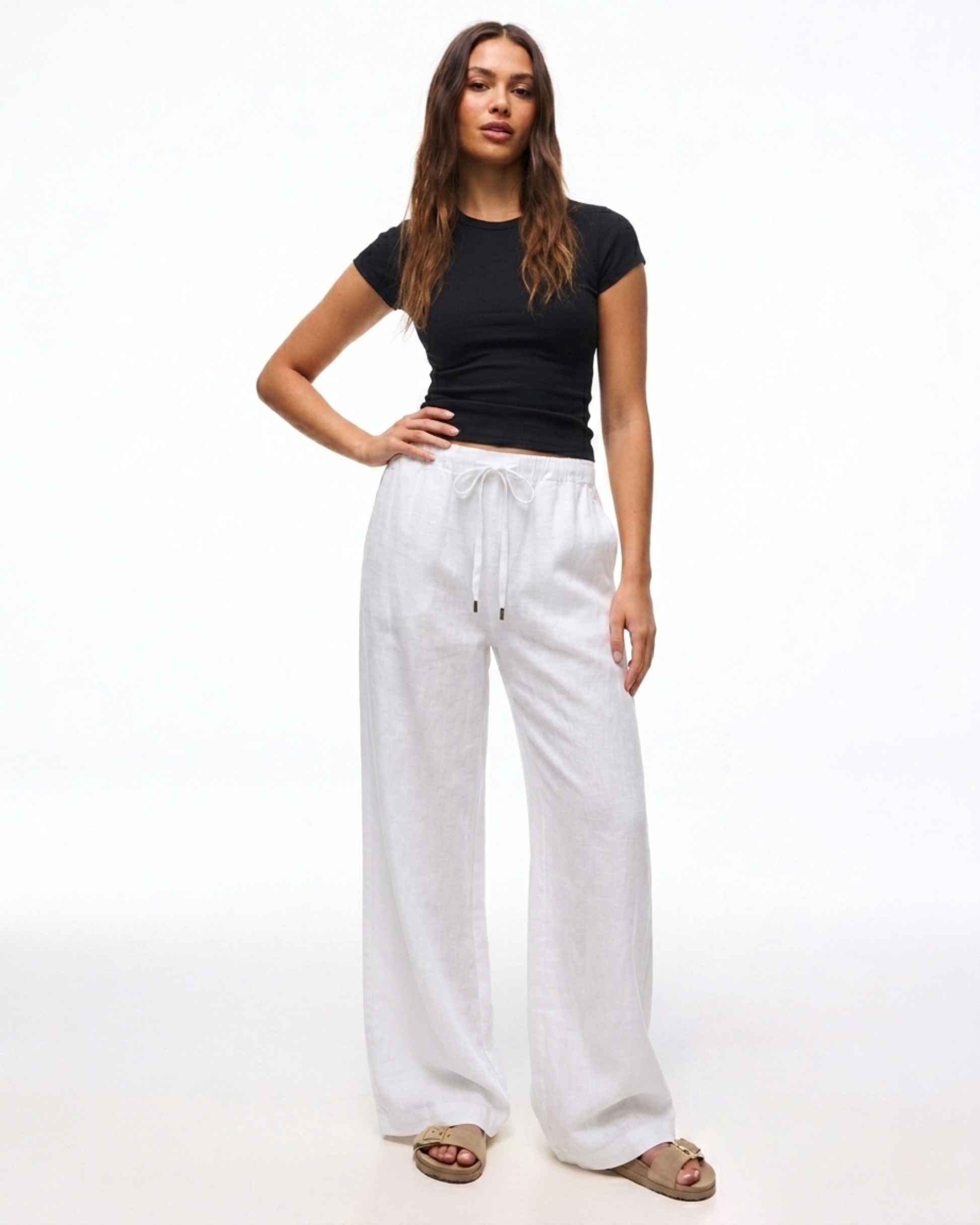 Damen trägt die weiße Leinenhose mit weitem Bein und Kordelzug.