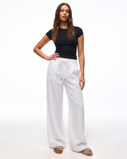 Damen trägt die weiße Leinenhose mit weitem Bein und Kordelzug.