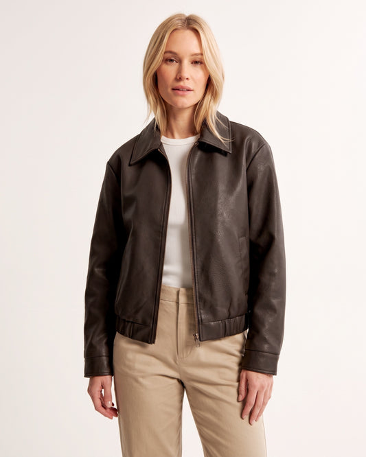 Model trägt dunkelbraune Vintage Kunstlederjacke mit Reverskragen zu beiger Hose