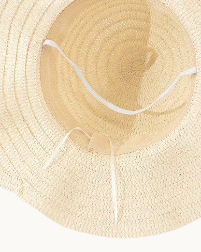 Nahaufnahme der Innenseite des ELEXUA „FLORA“ Strohhuts mit beigefarbenem Schweißband, weißem elastischem Kinnband und weißem Zugband zur Größenverstellung.
