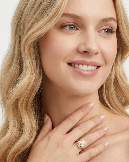 Nahaufnahme einer lächelnden Frau, deren Hand sanft auf dem Dekolleté liegt und das intensive Strahlen des floralen Kristall-Rings zeigt.