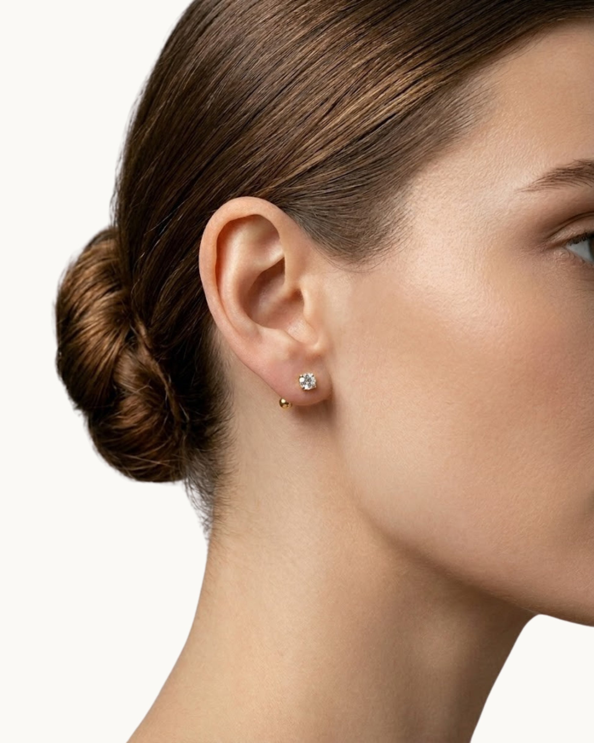 Seitenprofil einer Frau mit hochgesteckten Haaren, die den minimalistischen, gold-glänzenden Zirkonia-Stecker im Ohrläppchen trägt.
